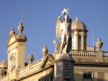 Genio Catalán Fountain with a winged male figure holding a star atop its pedestal and seated figures around the base