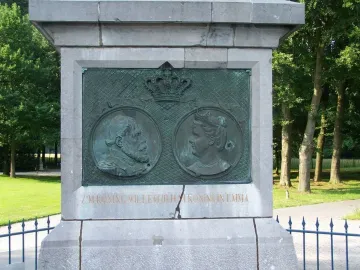 The Needle monument plaque with profile busts of King Willem III and Queen Emma beneath a crown.