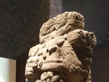Coatlicue stone statue with serpent heads, skull necklace, and carved textured body