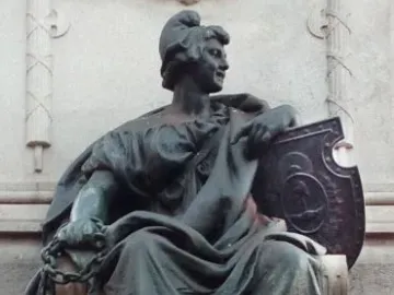 Bronze seated female figure on the Monument to Giuseppe Garibaldi, holding a broken chain and a decorated shield.
