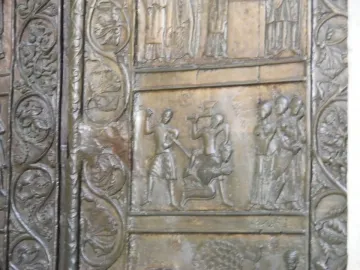 Close-up of the Gniezno Doors showing a bronze relief panel with figures and decorative swirling borders.