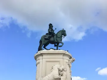 Equestrian statue of Joseph I on a tall ornate pedestal against a blue sky.