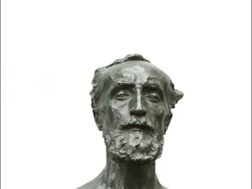 Bronze bust of Jules Dalou with a serious expression on a dark stone base.