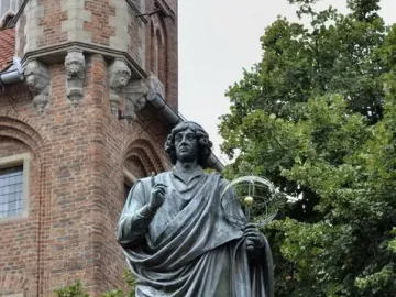 Nicolaus Copernicus Monument showing a bronze statue of a robed man pointing upward and holding a celestial globe.