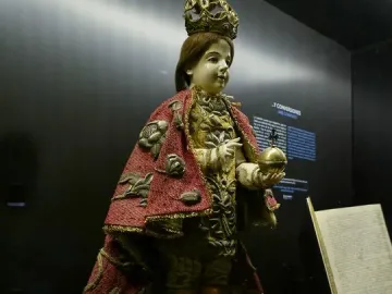 Santo Niño de Cebú statue with a golden crown, red embroidered cape, and golden orb with cross.