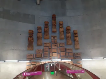Chemamull wooden figures arranged in a staggered pattern on a curved concrete wall.
