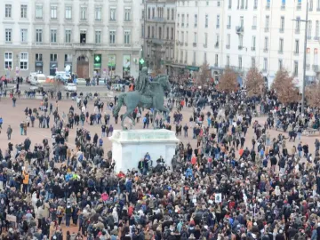 Louis XIV equestrian statue on a pedestal in a crowded public square.