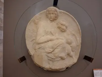 Michelangelo’s Pitti Tondo relief sculpture showing the Madonna and Child with the young Saint John behind glass.
