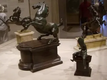 Bronze rearing horse sculpture beside a smaller mounted warrior figure on separate pedestals.