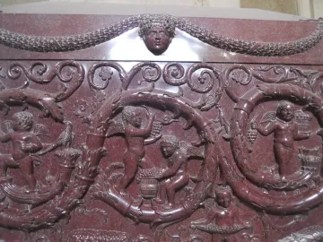 Sarcophagus of Constantina relief with winged putti harvesting grapes among swirling vine motifs and a central human head.