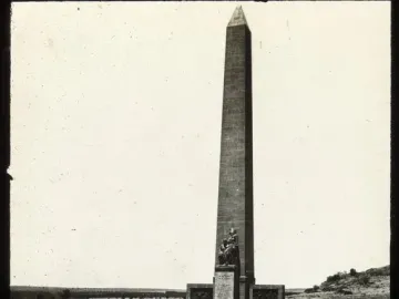 National Women\'s Monument with a tall obelisk and bronze figures at its base, seen from the steps below.