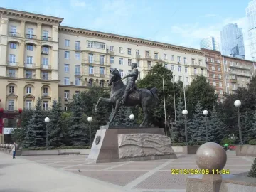 Pyotr Bagration Monument, a bronze equestrian statue on a stone pedestal in a paved plaza with trees and city buildings behind it.
