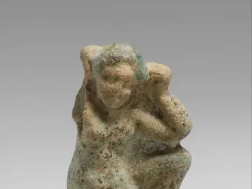 Crouching Venus statuette of a crouching female figure with one arm raised and the other across her body.