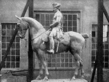 The Equestrian Monument of Frederick the Great shown as a large equestrian statue on a simple base in front of a building with many windows.