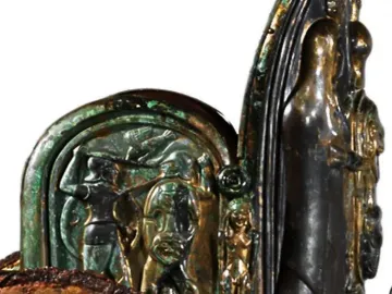 Detail of the Monteleone Chariot showing a bronze relief panel with figures in battle and ornate decorative elements.
