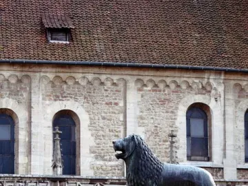 The Brunswick Lion statue stands on a stone pedestal in front of a historic stone building.