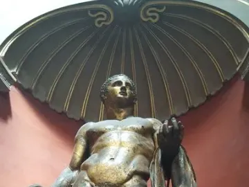 Hercules standing in a shell-shaped niche, holding a club and a lion skin, with a fig leaf covering his groin.