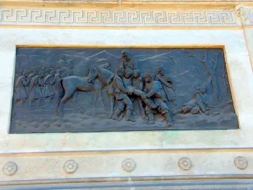 Bronze relief panel on the Marqués del Duero monument showing a battle scene with soldiers, a horse, and wounded figures.