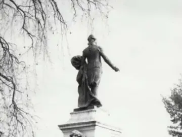 Marquis de Lafayette statue seen from behind, standing on a tall pedestal with figures around the base.