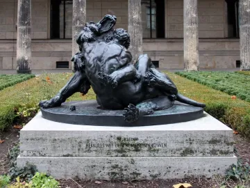Bronze sculpture of Hercules wrestling the Nemean Lion on a stone pedestal.