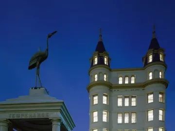 Temperance Fountain beside a brightly lit historic building at twilight, with a stone monument topped by a heron sculpture.