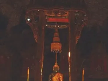 The Emerald Buddha seated on an ornate golden pedestal beneath a decorative canopy.