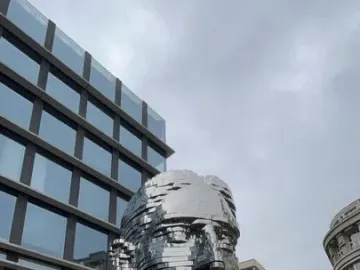 The rotating Head of Franz Kafka sculpture, a reflective segmented metallic head in an urban square.