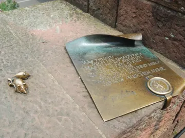 Bronze plaque on the Heidelberg Bridge Monkey sculpture with engraved German text and two small bronze mice on a stone block.