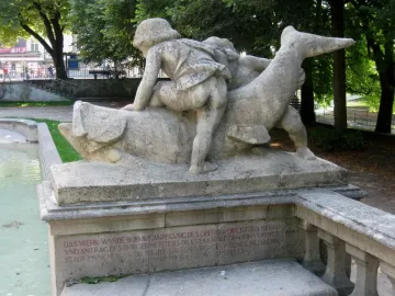 Rhine Water Fountain sculpture with two figures seated on a fish-like creature above a shallow pool.