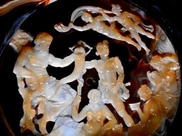 The Tazza Farnese carved gem shows a detailed relief scene with a bearded figure holding a horn among draped and partially nude figures.