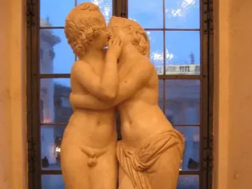 Marble sculpture of Cupid and Psyche embracing and kissing on a pedestal.