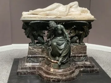 Shelley Memorial with a reclining white marble figure on a dark ornate base and seated draped mourner below.