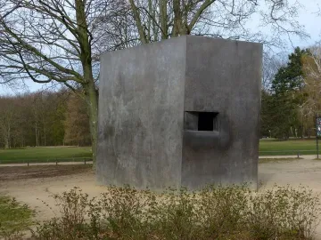 Memorial to Homosexuals Persecuted Under Nazism, a dark gray concrete block with a recessed opening in a park setting.
