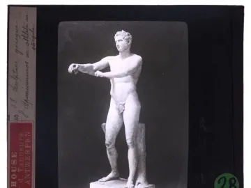 Classical Apoxyomenos statue of a nude male athlete extending his arms in a scraping pose against a dark background.
