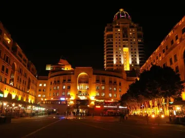 Nelson Mandela statue silhouetted in a brightly lit city square at night.