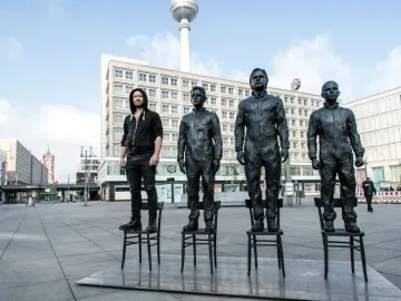 Anything to Say? sculpture figures standing on chairs in Berlin, with the TV Tower in the background.