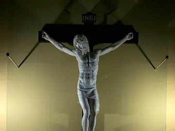 Benvenuto Cellini crucifix in white marble, showing Christ on a dark cross with INRI at the top.