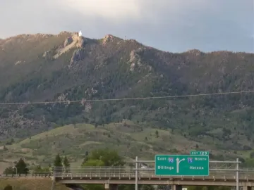 Our Lady of the Rockies statue standing on a rocky mountain peak with outstretched arms.