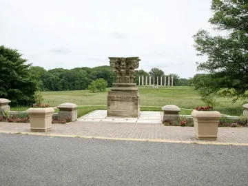 Capitol Columns standing across a grassy field with an ornate stone capital in the foreground