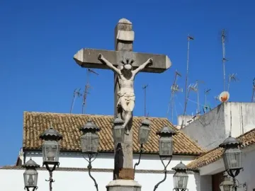 Christ of the Lanterns crucifix in Córdoba, illuminated by ornate black lanterns and surrounded by a decorative iron fence.