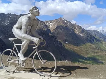 Géant du Tourmalet statue of a naked cyclist on a bicycle beside two cyclists and a Tourmalet sign