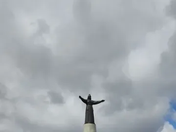 Mother Patroness statue with outstretched arms on a tall pedestal above a stepped plaza.