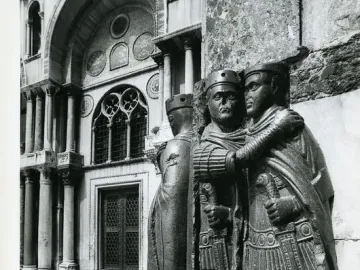 Portrait of the Four Tetrarchs, a dark carved group of four figures embracing, set before an ornate arched building.