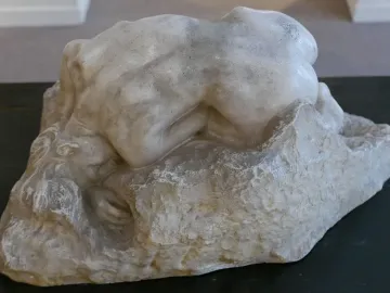 Rodin\'s Danaid sculpture showing a nude figure bent low over a rough base.