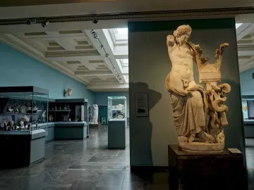 Apollo of Cyrene marble statue with draped lower body, a lyre, and a serpent at the base