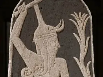 Stele of Baal with a horned deity raising a thunderbolt and holding a spear, with a smaller figure beside him.