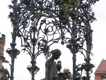 Gänseliesel Fountain with a bronze girl holding two geese on a stone pedestal beneath an ornate metal canopy.