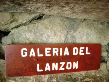 Wooden Galeria del Lanzón sign mounted against a rough stone wall.