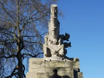 The Royal Artillery Memorial with a stone howitzer sculpture and bronze soldier figures on the base against a blue sky.