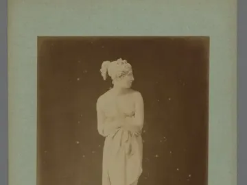 Venus Italica marble statue standing on a round pedestal, partially draped and facing right.